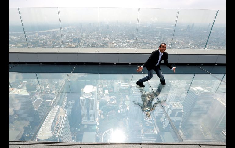 Un hombre posa para una foto sobre un piso de cristal desde el mirador del rascacielos King Power Mahanakhon de Bangkok, Tailandia. El edificio, de 314 metros de altura, abrió el mirador en el piso 78 para convertirse en el más alto del todo el país. EFE/N. Sangnak
