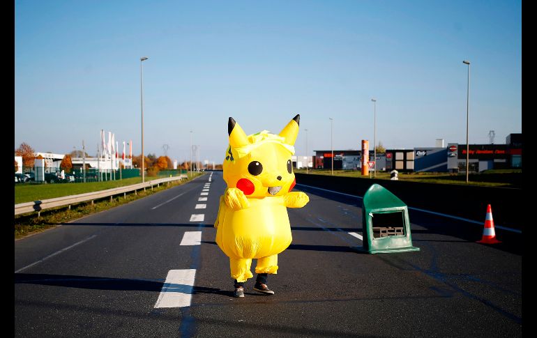 Una persona disfrazada de Pikachu camina por una calle bloqueada por manifestantes de los 