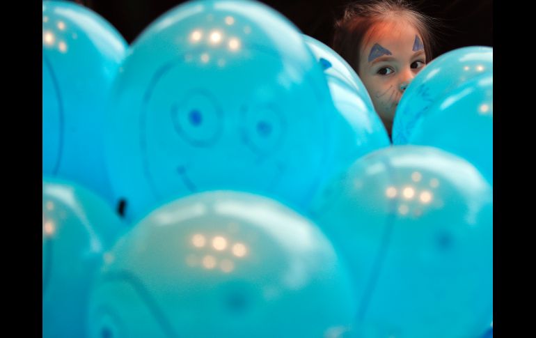 Antonia, de 6 años, se asoma entre globos en Bucarest, Rumania, durante un evento de Unicef para celebrar el Día Universal del Niño. AP/V. Ghirda