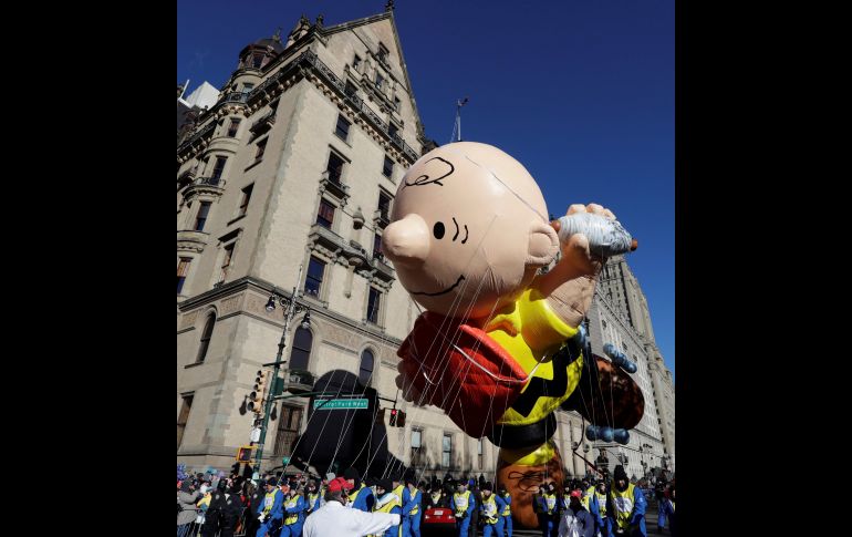 Varios operarios dirigen el globo gigante del personaje Charlie Brown.