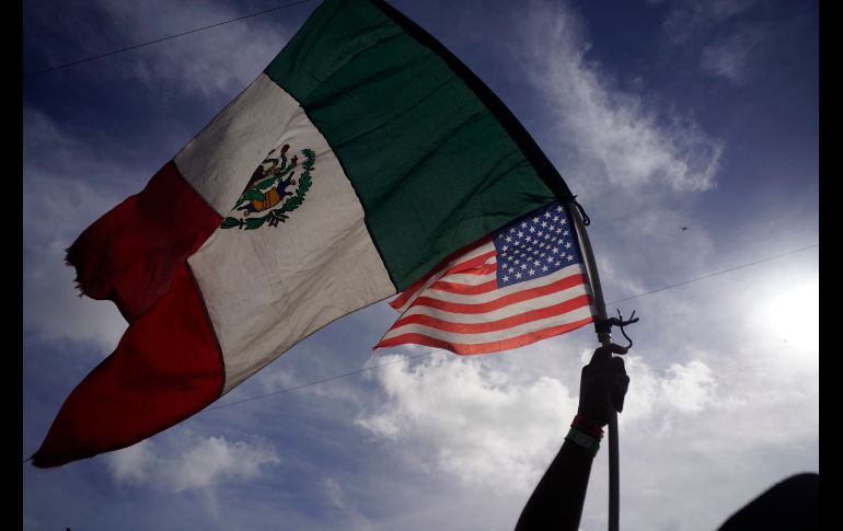 Un hondureño ondean banderas de México y Estados Unidos. AP/R. Espinosa