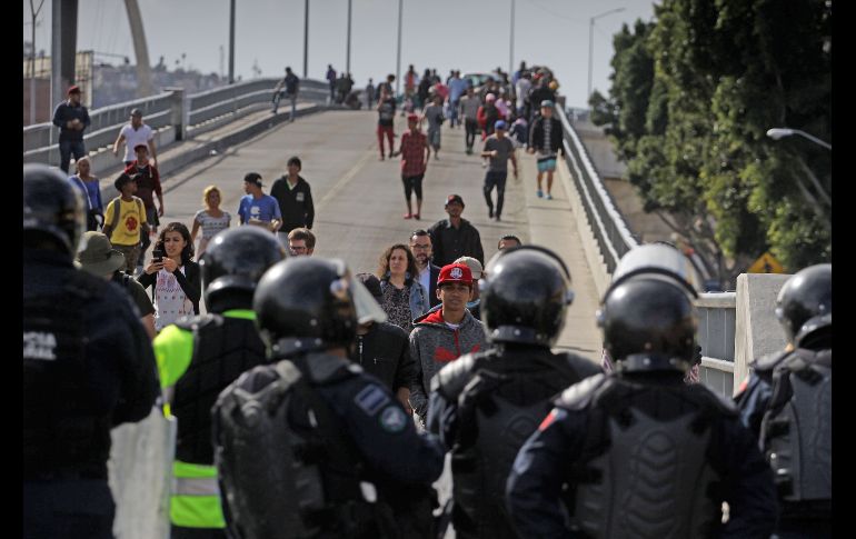 Agentes federales y municipales mexicanos bloquean a migrantes que se dirigen a la garita peatonal de El Chaparral.