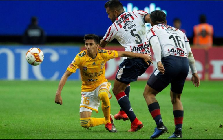 El jugador de Chivas Hedgardo Marín (c) disputa el balón con Raúl Torres (i) de Tigres. EFE/F. Guasco