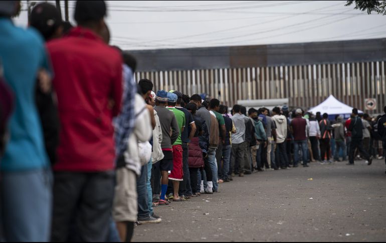 Migrantes centroamericanos hacen fila para buscar comida fuera de un refugio en Tijuana. AFP / P. Pardo