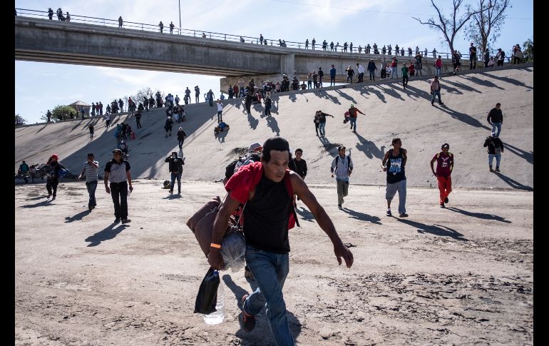 Migrantes cruzan el lecho casi seco de un río en Tijuana para intentar llegar al cruce peatonal de El Chaparral. AFP/G. Arias