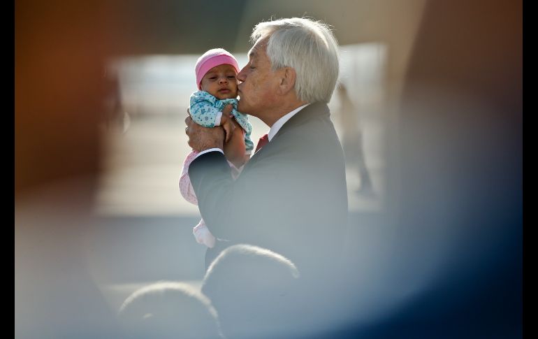 El presidente de Chile, Sebastián Piñera, besa a un bebé al recibir a un grupo de repatriados en el aeropuerto internacional de Santiago. Casi 100 chilenos y sus familiares dejaron Venezuela, que enfrenta una severa crisis. AP/E. Félix