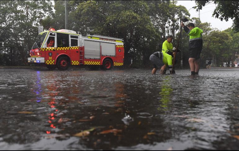 Trabajadores intentan destapar un desagüe bajo la lluvia en Sídney, Nueva Gales del Sur. EFE/D. Pateman