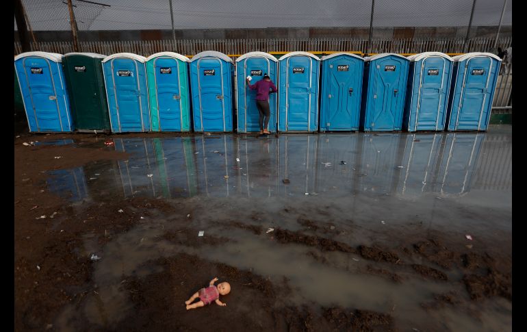 Una mujer se dirige a un baño en una zona encharcada por la lluvia, dentro de una unidad deportiva en Tijuana, el cual sirve de albergue e integrantes de la caravana migrante. Una fuerte lluvia que cayó este jueves afectó colchonetas y cobijas al ras del suelo. AP/R. Blackwell