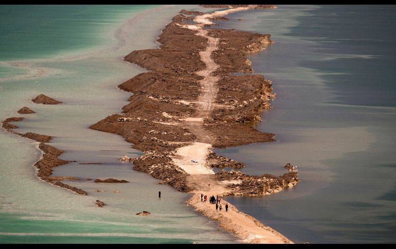 Turistas caminan por una barrera de arena en el Mar Muerto, en Ein Bokek, Israel. EFE/A. Safadi