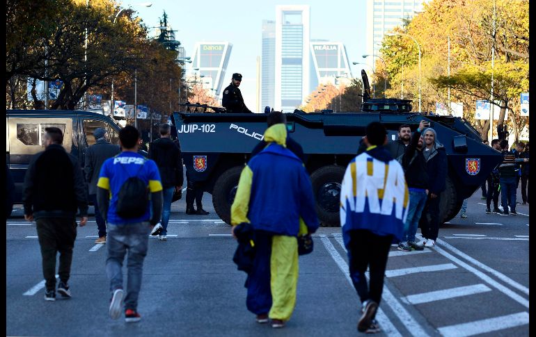 Policías antimotines vigilan mientras seguidores del Boca Juniors caminan por el Paseo de la Castellana en Madrid, cerca del estadio Santiago Bernabéu, previo al partido de ida de la Copa Libertadores entre el Boca y el River Plate argentinos.AFP/O. Del Pozo