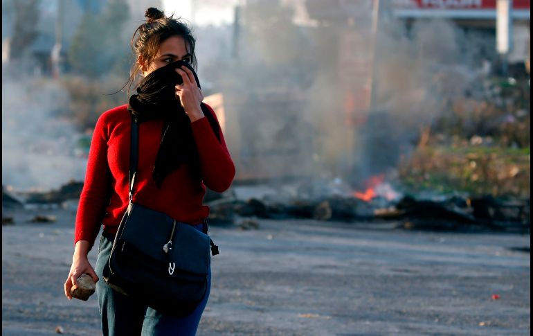 Una palestina se cubre el rostro durante enfrentamientos con tropas israelíes en Ramallah, cerca del asentamiento judío de Beit El, en la zona ocupada de Cisjordania. AFP/A. Momani