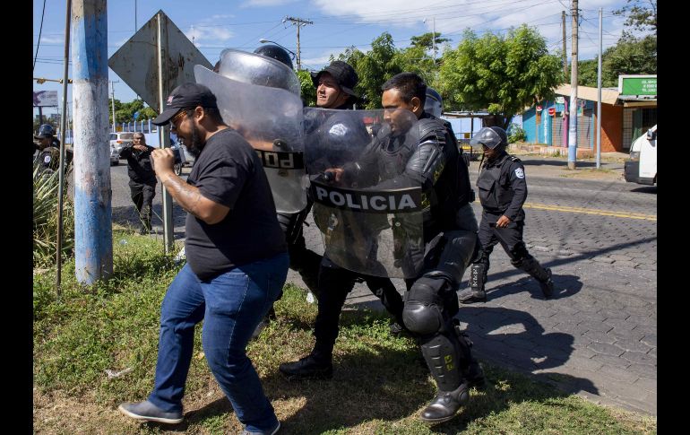 Agentes de la policía nacional repliegan al periodista Nestor Arce del semanario Confidencial. EFE / J. Torre