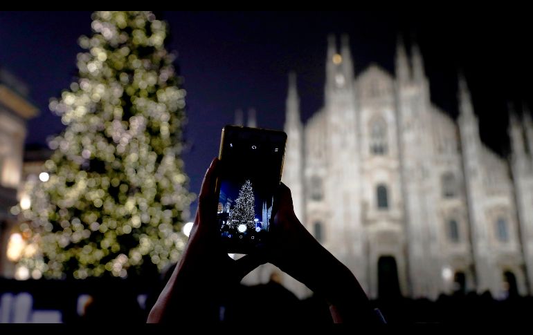 Una mujer toma una foto del árbol de Navidad frente a la catedral gótica de Milán, Italia. AP/A. Calanni