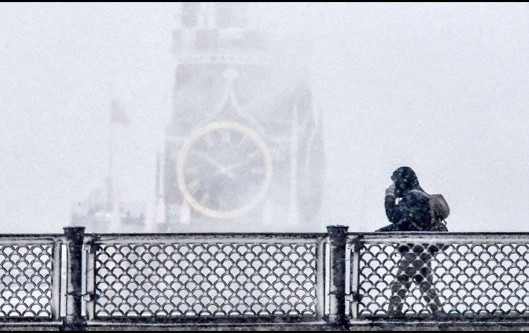 Un peatón cruza un puente frente a la torre Spasskaya del Kremlin, durante una nevada en Moscú. La capital rusa registra temperaturas de menos 14 grados centígrados. AFP/Y. Kadobnov
