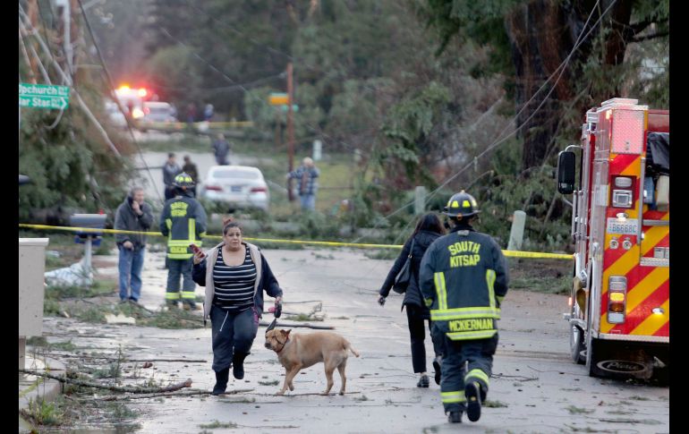 Habitantes y personal de emergencias se ven en Port Orchard, en el estado de Washington, luego de que un tornado golpeó la población, causando daños en varias casas. AP/Kitsap Sun/L. Steagall