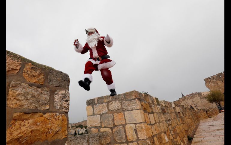 Un hombre en atuendo de Santa Claus camina por los muros de la Vieje Ciudad de Jerusalén. AFP/G. Tibbon