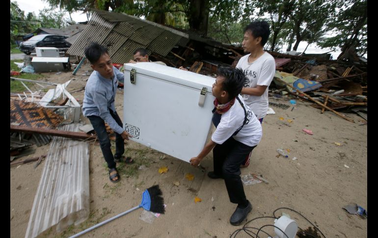 Vecinos cargan un refrigerador recuperado de entre los escombros en Carita.