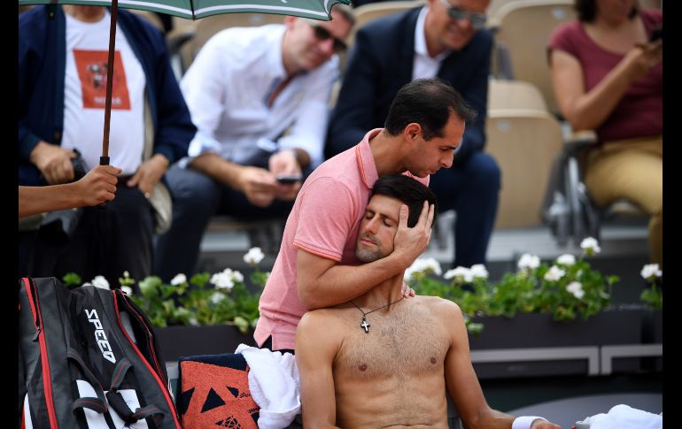 El tenista serbio Novak Djokovic recibe tratamiento de un entrenador, durante un descanso en partido de cuartos de final del Roland Garros disputado en París el 5 de junio. AFP/E. Feferberg
