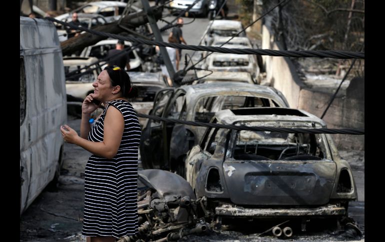 Una mujer reacciona entre vehículos quemados en la ciudad griega de Mati, el 24 de julio. Los incendios forestales en la localidad dejaron al menos 94 personas muertas y más de 180 heridas. AP/T. Stavrakis