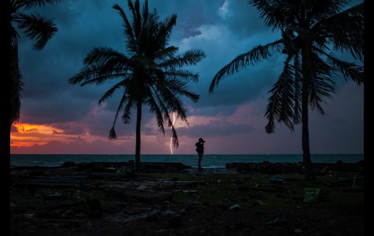 Un fotoperiodista se ve al amanecer en Carita, Indonesia, una localidad turística afectada por el tsunami del sábado. AP/F. Chaniago