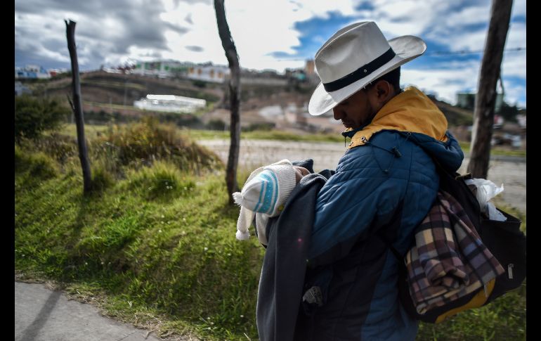 El venzolano Richard Lomelly carga a un bebé el 23 de agosto, durante el trayecto de un grupo de migrantes de Pasto a Ipiales, en Colombia, con el fin de llegar a Perú. Miles de venezolanos que huyen de la crisis en su país intentaban entrar a Perú previo a la exigencia de portar un pasaporte. AFP/L. Robayo