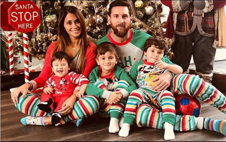 La familia está sentada frente a un enorme árbol de Navidad y un Papá Noel. ESPECIAL