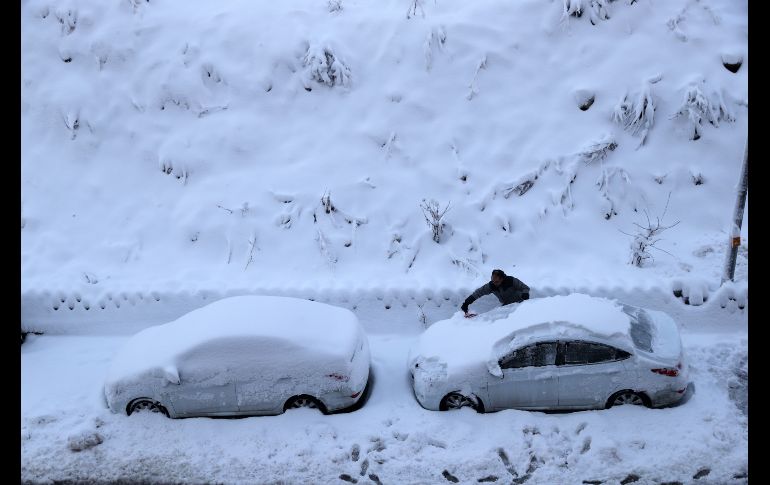 Un habitante quita nieve de su auto en Ankara, Turquía. AFP/A. Altan