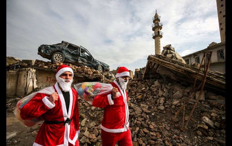 Un par de jóvenes se disfrazaron de Santa Claus para repartir juguetes en la zona en ruinas de la ciudad, devastada por la guerra. AFP/A. Al-Rubaye