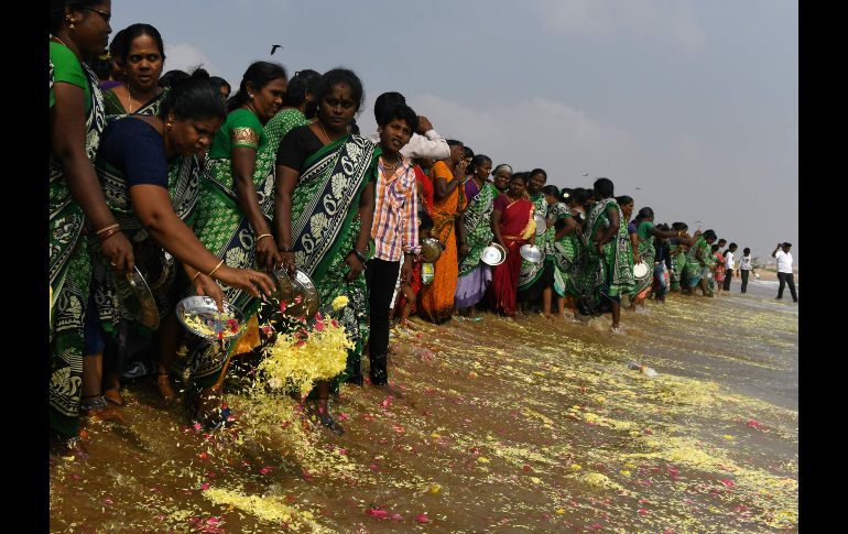 Mujeres arrojan flores al mar en Chennai, India, en una ceremonia para conmemorar  a las víctimas del tsunami de 2004. El desastre natural causó 230 mil  muertos en una docena de países bañados por el océano Índico. AFP/A. Sankar