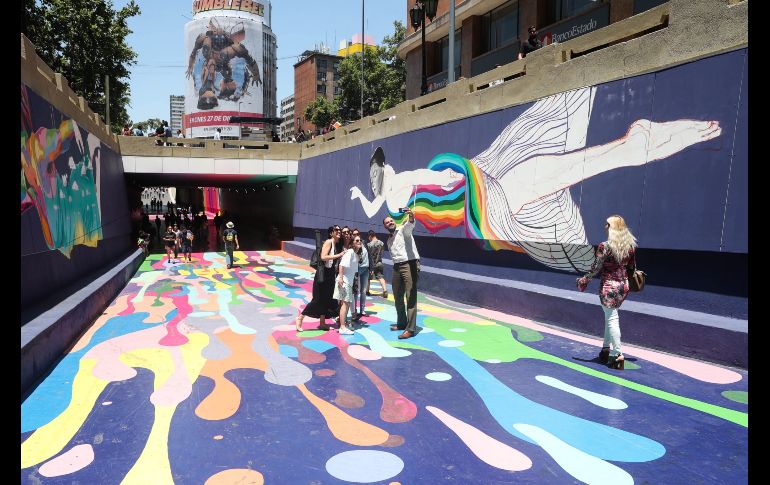 Transeúntes recorren el céntrico paseo Bandera mientras se toman fotografías con los coloridos murales que lo decoran, en Santiago de Chile. EFE/A. Valdés
