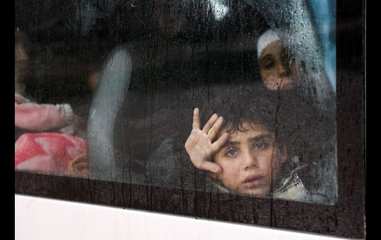 Un niño sirio mira desde un autobús que transporta a ciudadanos al punto de revisión de Abu Duhur, que separa las áreas en control de los rebeldes y del gobierno. AFP/G. Ourfalian