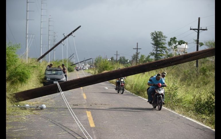 Habitantes pasan junto a postes de electricidad caídos en Escuinapa, Sinaloa, tras el paso del huracán 