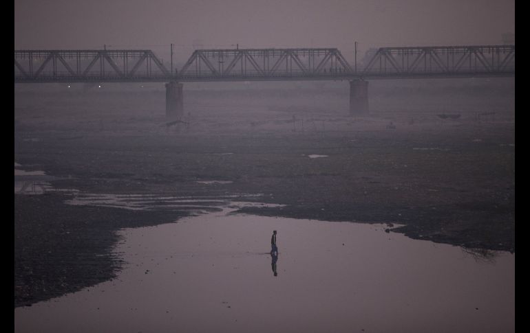 Un hombre camina por el río Yamuna entre una densa capa de contaminación en Agra, India. AFP/X. Galiana
