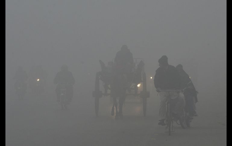 Paquistaníes pasan por un camino entre una fuerte contaminación en Lahore. AFP/A. Ali