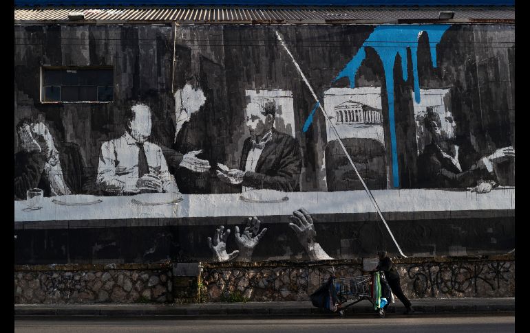 Un hombre pasa junto a un mural del artista callejero iNo en el centro de Atenas, Grecia. AP/P. Giannakouris