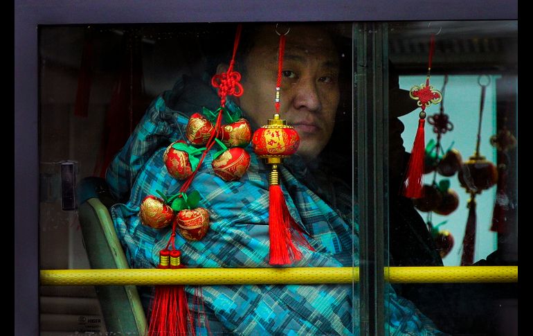 Un pasajero mira desde una ventana de autobús decorada por el año nuevo chino en Pekín. AP/A. Wong