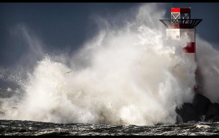 Olas azotan un faro en IJmuiden, en la costa holandesa, durante la primera tormenta del año. AFP/ANP/K. Van Weel