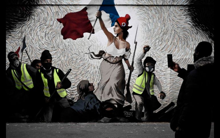 Un hombre toma una foto de un mural del artista callejero PBOY en París, el cual muestra a manifestantes de los 