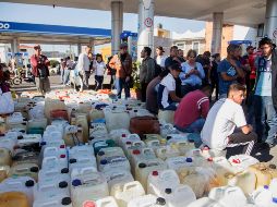 Docenas de personas en esperan a que lleguen las pipas con combustibles para llenar sus bidones. AFP/E. Castro