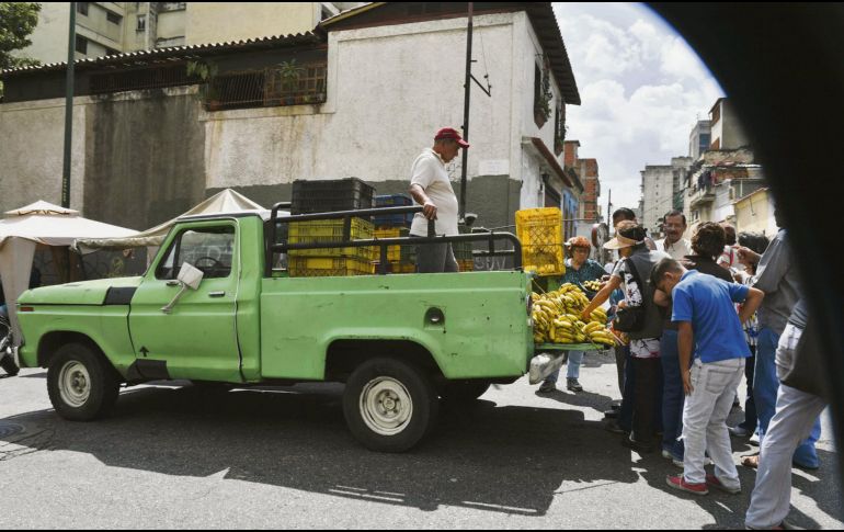 Un grupo de personas busca alimentos en los alrededores de un mercado de la capital venezolana. AFP