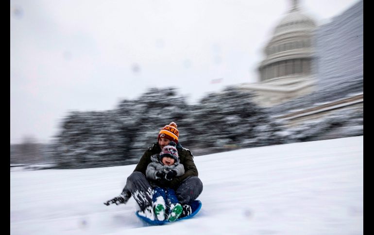 Una familia se desliza en la nieve frente al Capitolio estadounidense en Washington, DC, tras la intensa nevada de anoche. AFP/A. Edelman