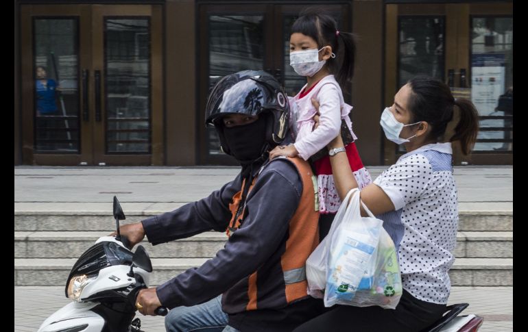 Habitantes portan cubrebocas durante un traslado en moto en la capital tailandesa. AFP/R. Gacad