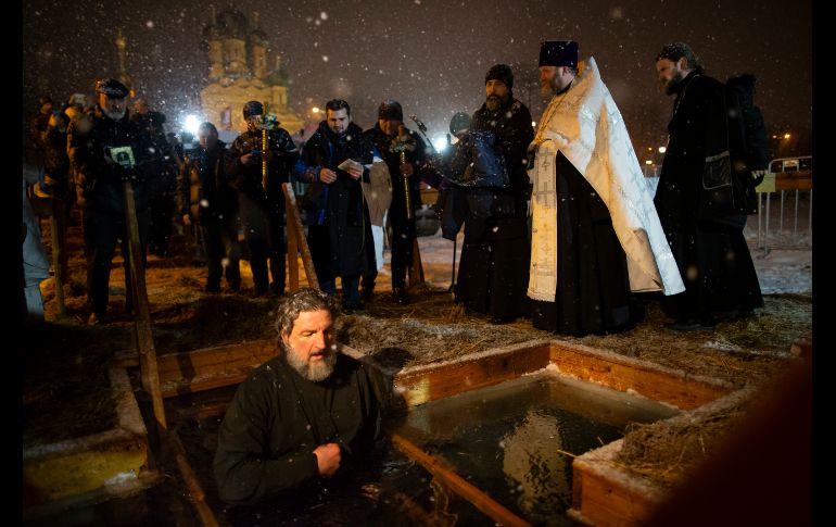 Un cura ortodoxo se persigna mientras está en el agua helada durante la celebración de la Epifanía. AP / A. Zemlianichenko