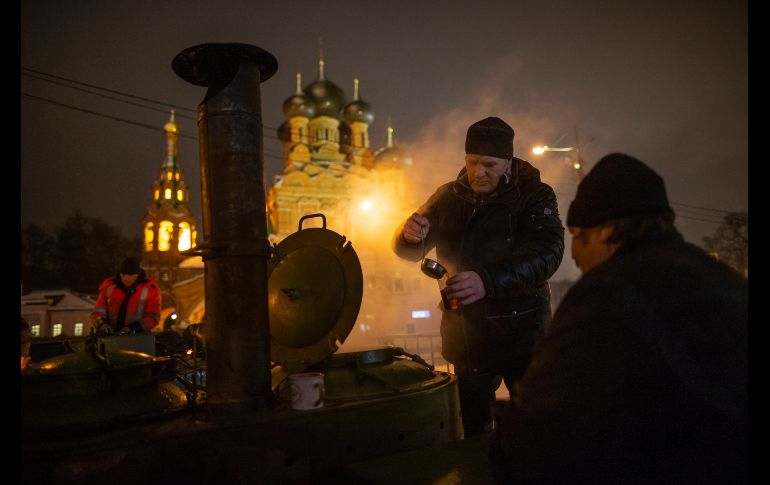 Un empleado municipal sirve té caliente para los participantes de la epifanía. AP / A. Zemlianichenko