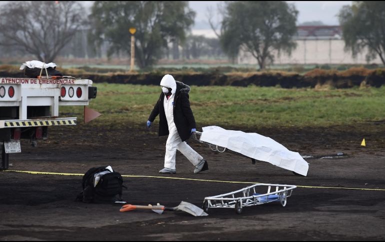 Un experto forense mueve un cuerpo encontrado en la zona de la tragedia. AFP / A. Estrella