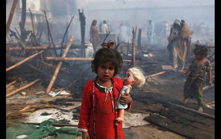 Una  niña mira mientras sostiene a su muñeca en las ruinas de su casa quemada luego de un fuerte incendio en Karachi, Pakistán. AP/F. Khan