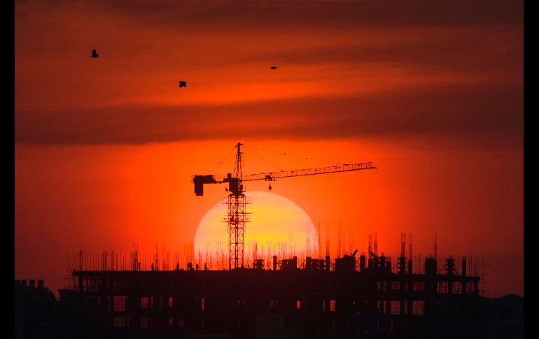 Trabajadores se observan en un edificio en construcción en Rangún, Birmania, durante la puesta de Sol. AFP/Y. Aung Thu