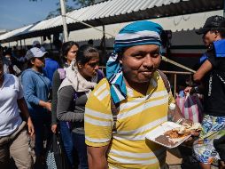 Migrantes hondureños comen mientras continúan con los trámites para obtener la tarjeta humanitaria del Instituto Nacional de Migración. EFE/L. Villalobos