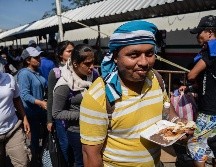 Migrantes hondureños comen mientras continúan con los trámites para obtener la tarjeta humanitaria del Instituto Nacional de Migración. EFE/L. Villalobos