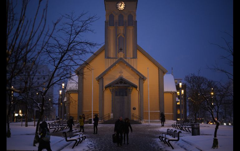 Personas caminan junto a un templo en Tromso. En esta época del año, la luz del día es de apenas dos horas, entre las 11:00 y 13:00 horas. AFP/O. Morin